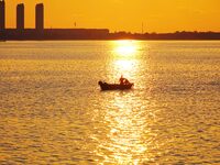 A fishing boat rides in Tangdao Bay illuminated by the rising sun in Qingdao, China, on September 9, 2024. (