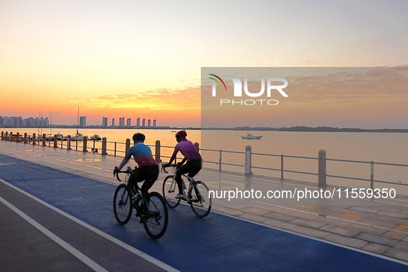 Cyclists ride on Tangdao Bay under the sunrise in Qingdao, China, on September 9, 2024. 