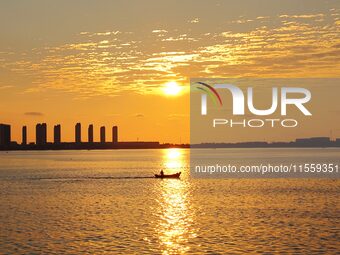 A fishing boat rides in Tangdao Bay illuminated by the rising sun in Qingdao, China, on September 9, 2024. (