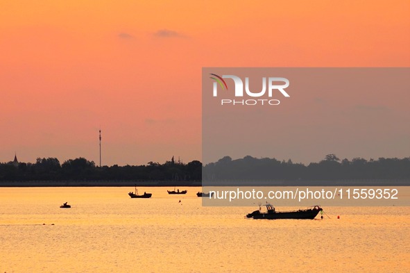 A fishing boat rides in Tangdao Bay illuminated by the rising sun in Qingdao, China, on September 9, 2024. 