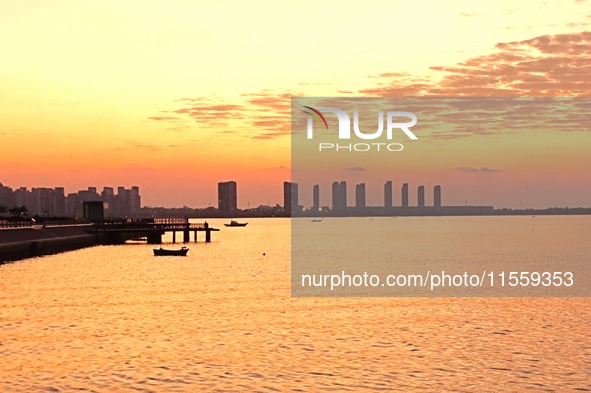 A fishing boat rides in Tangdao Bay illuminated by the rising sun in Qingdao, China, on September 9, 2024. 