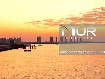 A fishing boat rides in Tangdao Bay illuminated by the rising sun in Qingdao, China, on September 9, 2024. (