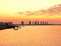 A fishing boat rides in Tangdao Bay illuminated by the rising sun in Qingdao, China, on September 9, 2024. (