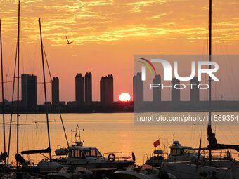 A fishing boat rides in Tangdao Bay illuminated by the rising sun in Qingdao, China, on September 9, 2024. (