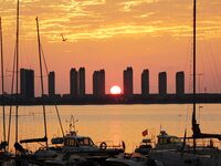 A fishing boat rides in Tangdao Bay illuminated by the rising sun in Qingdao, China, on September 9, 2024. (