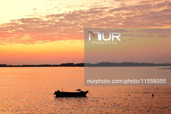 A fishing boat rides in Tangdao Bay illuminated by the rising sun in Qingdao, China, on September 9, 2024. 