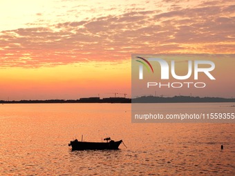 A fishing boat rides in Tangdao Bay illuminated by the rising sun in Qingdao, China, on September 9, 2024. (