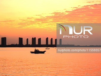 A fishing boat rides in Tangdao Bay illuminated by the rising sun in Qingdao, China, on September 9, 2024. (