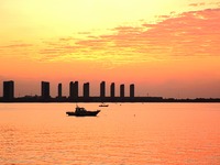 A fishing boat rides in Tangdao Bay illuminated by the rising sun in Qingdao, China, on September 9, 2024. (