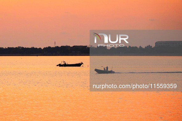 Fishing boats ride in Tangdao Bay illuminated by the rising sun in Qingdao, China, on September 9, 2024. 