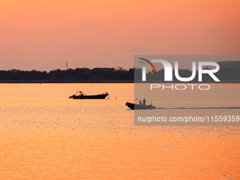 Fishing boats ride in Tangdao Bay illuminated by the rising sun in Qingdao, China, on September 9, 2024. (