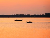 Fishing boats ride in Tangdao Bay illuminated by the rising sun in Qingdao, China, on September 9, 2024. (