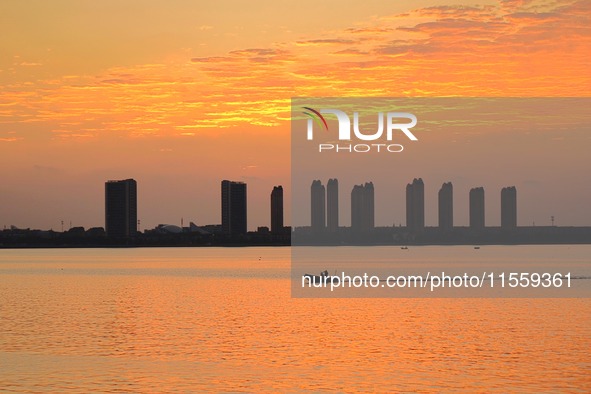 A fishing boat rides in Tangdao Bay illuminated by the rising sun in Qingdao, China, on September 9, 2024. 