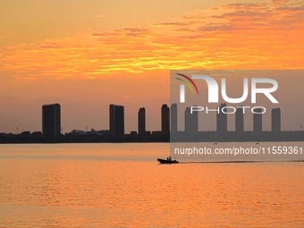 A fishing boat rides in Tangdao Bay illuminated by the rising sun in Qingdao, China, on September 9, 2024. (