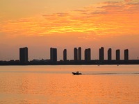 A fishing boat rides in Tangdao Bay illuminated by the rising sun in Qingdao, China, on September 9, 2024. (