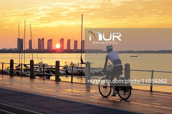 Cyclists ride on Tangdao Bay under the sunrise in Qingdao, China, on September 9, 2024. 