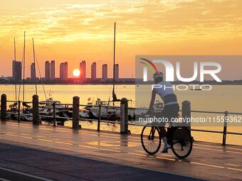 Cyclists ride on Tangdao Bay under the sunrise in Qingdao, China, on September 9, 2024. (