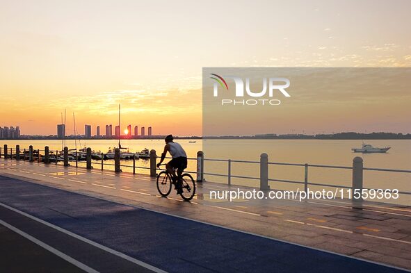 Cyclists ride on Tangdao Bay under the sunrise in Qingdao, China, on September 9, 2024. 