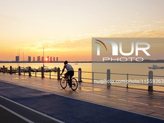 Cyclists ride on Tangdao Bay under the sunrise in Qingdao, China, on September 9, 2024. (