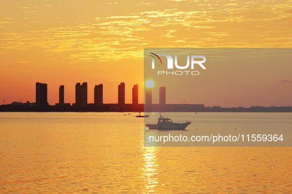 A fishing boat rides in Tangdao Bay illuminated by the rising sun in Qingdao, China, on September 9, 2024. 