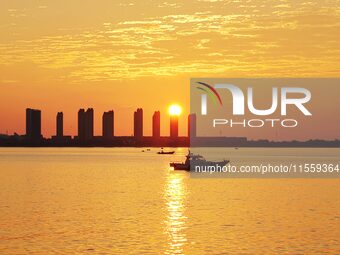 A fishing boat rides in Tangdao Bay illuminated by the rising sun in Qingdao, China, on September 9, 2024. (