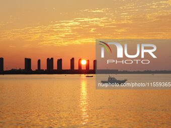 A fishing boat rides in Tangdao Bay illuminated by the rising sun in Qingdao, China, on September 9, 2024. (