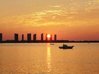 A fishing boat rides in Tangdao Bay illuminated by the rising sun in Qingdao, China, on September 9, 2024. (