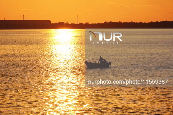 A fishing boat rides in Tangdao Bay illuminated by the rising sun in Qingdao, China, on September 9, 2024. 