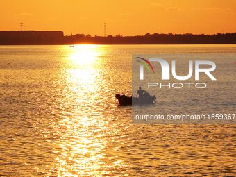 A fishing boat rides in Tangdao Bay illuminated by the rising sun in Qingdao, China, on September 9, 2024. (