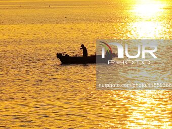 A fishing boat rides in Tangdao Bay illuminated by the rising sun in Qingdao, China, on September 9, 2024. (