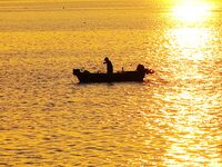 A fishing boat rides in Tangdao Bay illuminated by the rising sun in Qingdao, China, on September 9, 2024. (