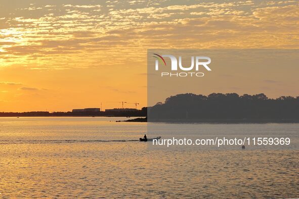 A fishing boat rides in Tangdao Bay illuminated by the rising sun in Qingdao, China, on September 9, 2024. 