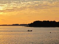 A fishing boat rides in Tangdao Bay illuminated by the rising sun in Qingdao, China, on September 9, 2024. (