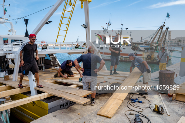 Sailors and workers prepare the base joining three fishing boats that house the statue of Our Lady of Martyrs for the patronal feast in Molf...