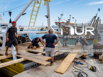 Sailors and workers prepare the base joining three fishing boats that house the statue of Our Lady of Martyrs for the patronal feast in Molf...