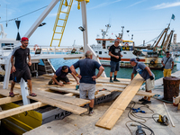 Sailors and workers prepare the base joining three fishing boats that house the statue of Our Lady of Martyrs for the patronal feast in Molf...