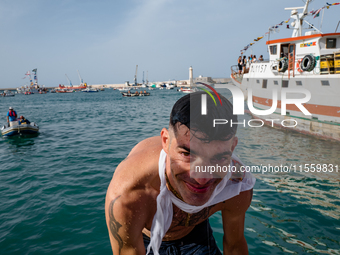 A sailor dives into the sea to greet the statue of Our Lady of Martyrs on the occasion of the patronal feast day in Molfetta, Italy, on Sept...