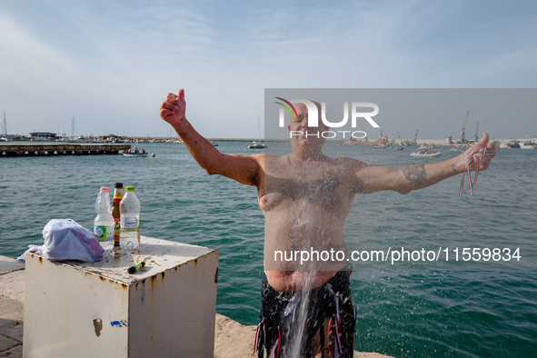 A sailor gets wet after diving into the sea to greet the statue of Our Lady of Martyrs on the occasion of the patronal feast day in Molfetta...