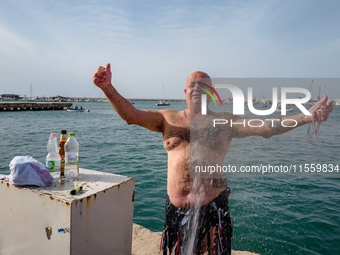 A sailor gets wet after diving into the sea to greet the statue of Our Lady of Martyrs on the occasion of the patronal feast day in Molfetta...