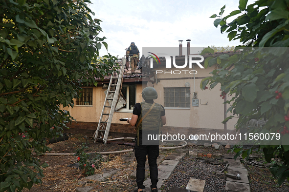 Police officers inspect the house for damage after Russian shelling with cluster munitions in Derhachi, Kharkiv region, north-eastern Ukrain...