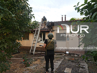 Police officers inspect the house for damage after Russian shelling with cluster munitions in Derhachi, Kharkiv region, north-eastern Ukrain...