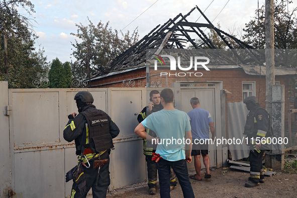 Civilians and rescuers are outside a house damaged as a result of Russian shelling with cluster munitions in Derhachi, Kharkiv region, north...