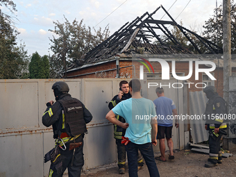 Civilians and rescuers are outside a house damaged as a result of Russian shelling with cluster munitions in Derhachi, Kharkiv region, north...