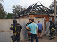 Civilians and rescuers are outside a house damaged as a result of Russian shelling with cluster munitions in Derhachi, Kharkiv region, north...