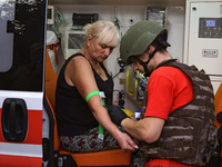 A medical worker provides aid to a woman injured as a result of Russian shelling with cluster munitions in Derhachi, Kharkiv region, north-e...