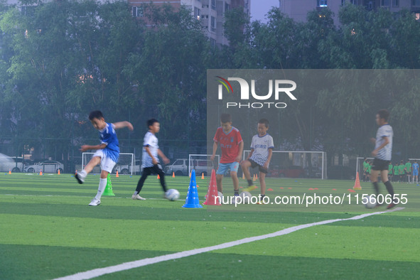 Children practice soccer at the evening soccer field of Capital Sport University in Beijing, China, on September 9, 2024. 