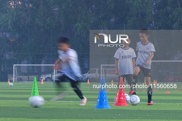 Children practice soccer at the evening soccer field of Capital Sport University in Beijing, China, on September 9, 2024. 