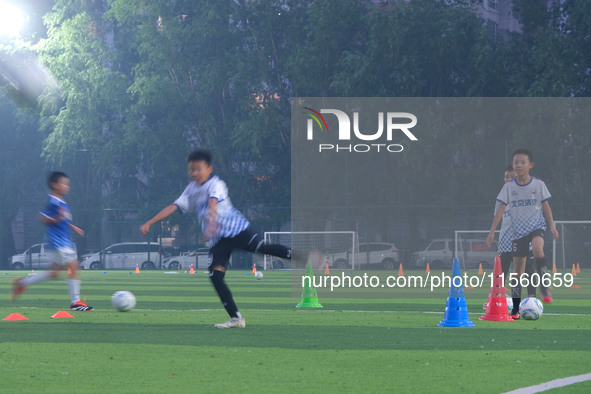 Children practice soccer at the evening soccer field of Capital Sport University in Beijing, China, on September 9, 2024. 