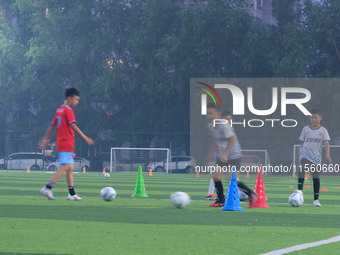 Children practice soccer at the evening soccer field of Capital Sport University in Beijing, China, on September 9, 2024. (