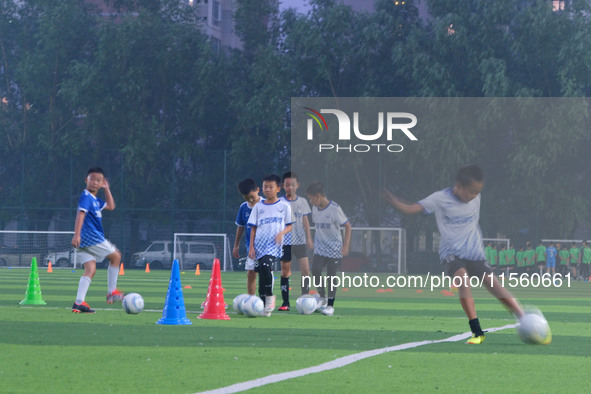 Children practice soccer at the evening soccer field of Capital Sport University in Beijing, China, on September 9, 2024. 